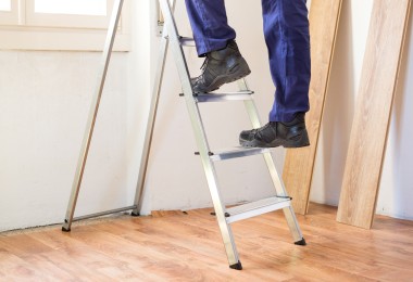 Person steht auf einer Leiter.